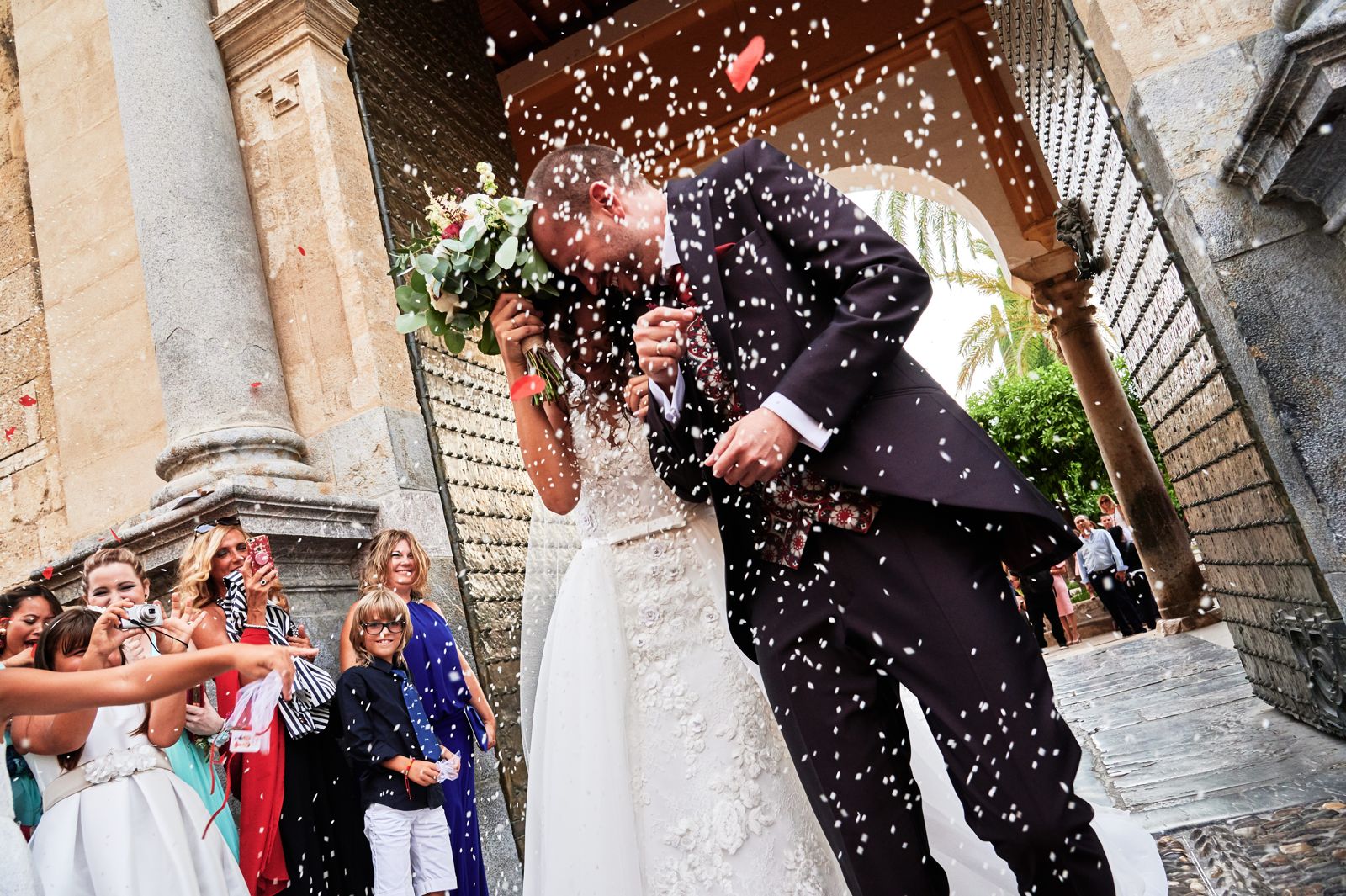 Los novios se protegen de la lluvia de arroz a la salida de la ceremonia